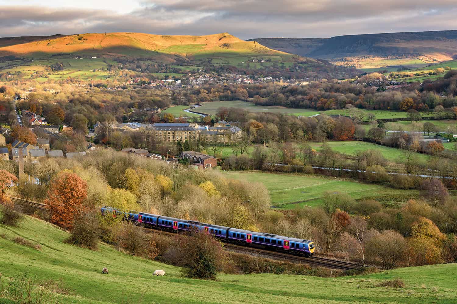 photo of rural scene with train in foreground and village and hills in background