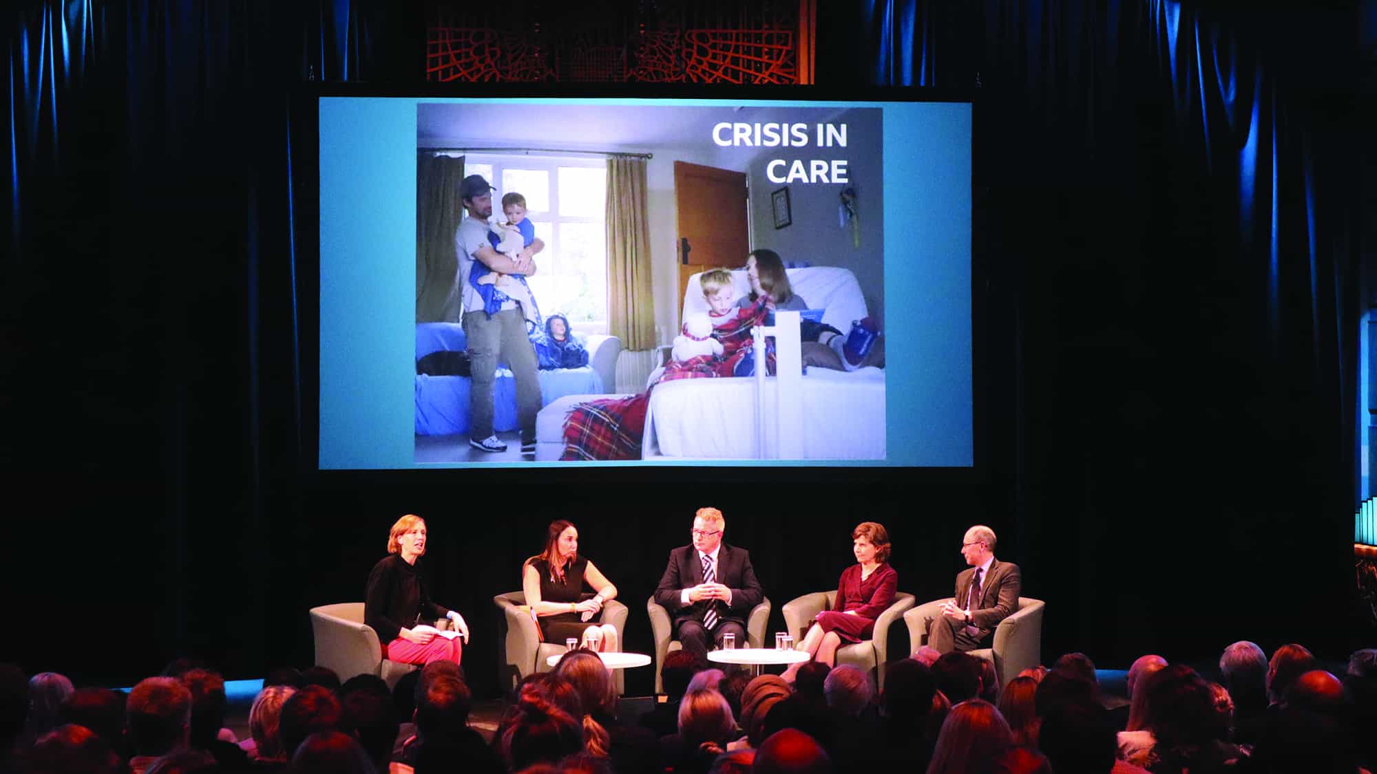a panel of members discussing crisis in care to an audience