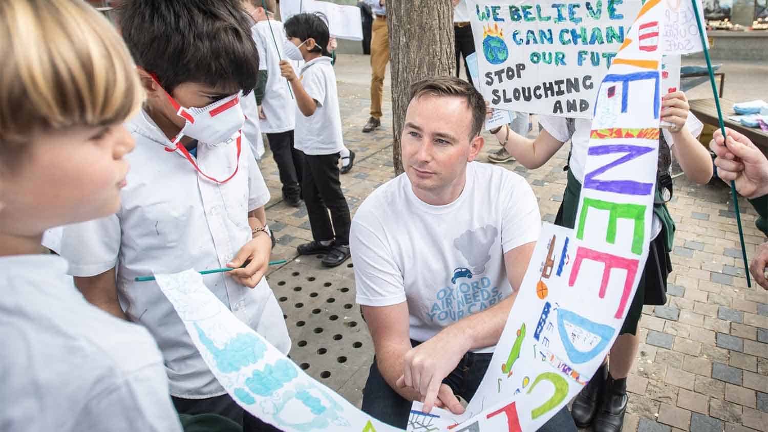 Cllr Tom Hayes talking with children making posters