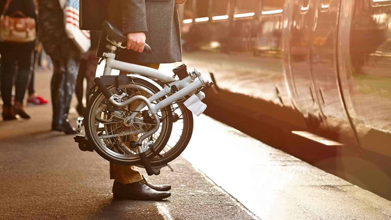 Man with fold up bike getting on a train