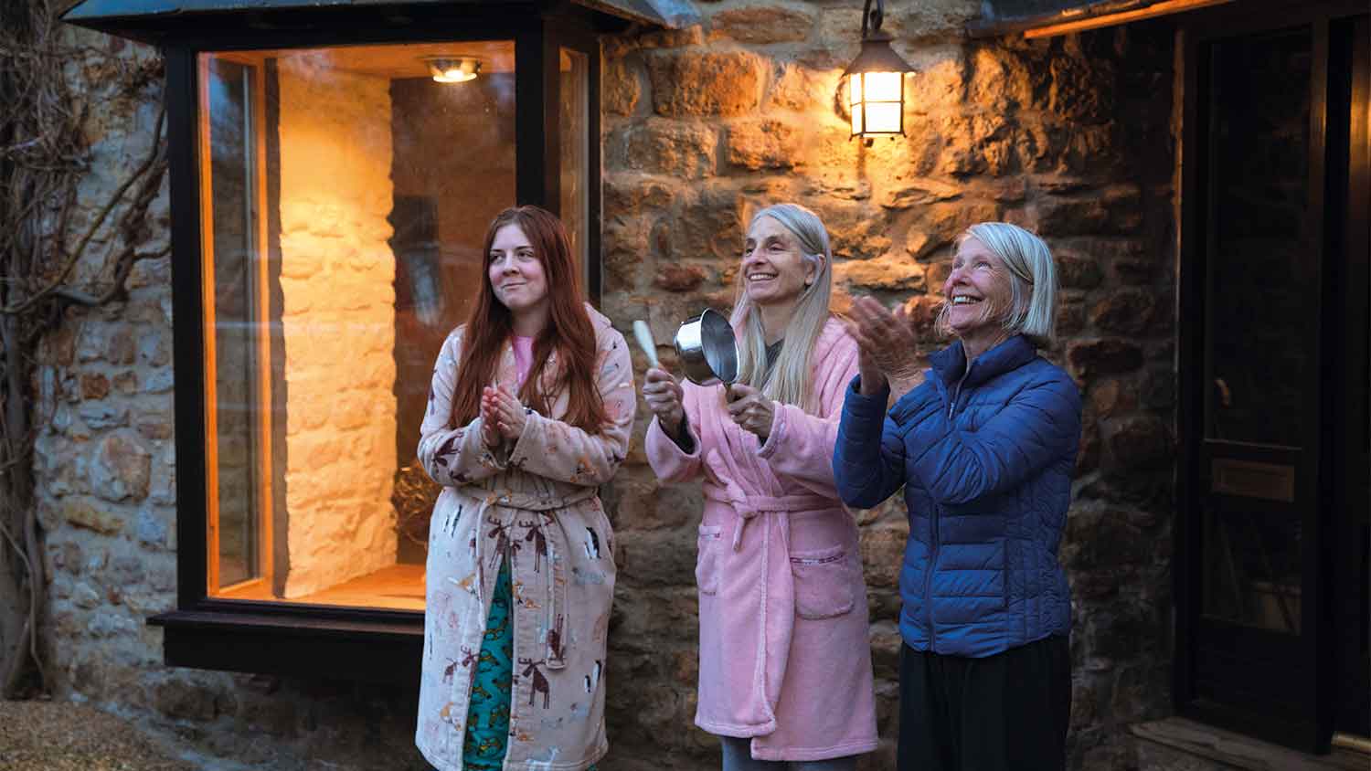 Three women applauding key workers outside their home