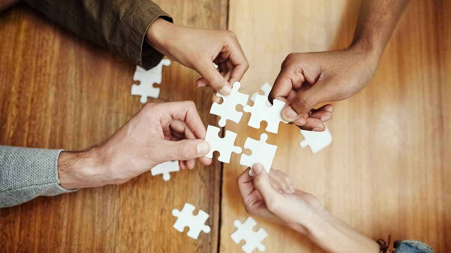 Hands putting together puzzles