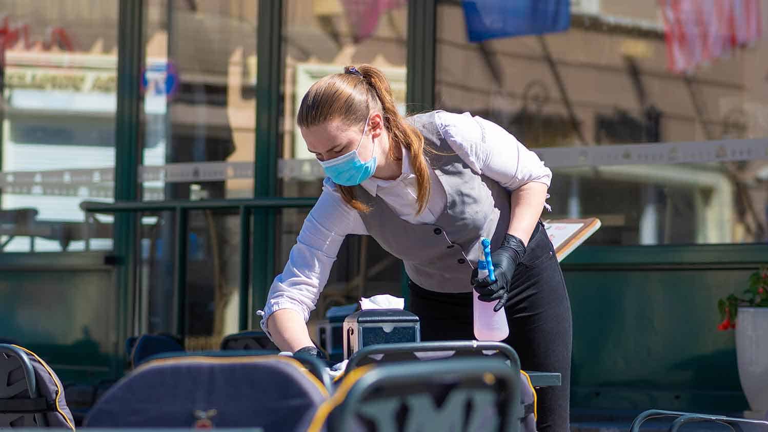 Waitress diisinfecting a table