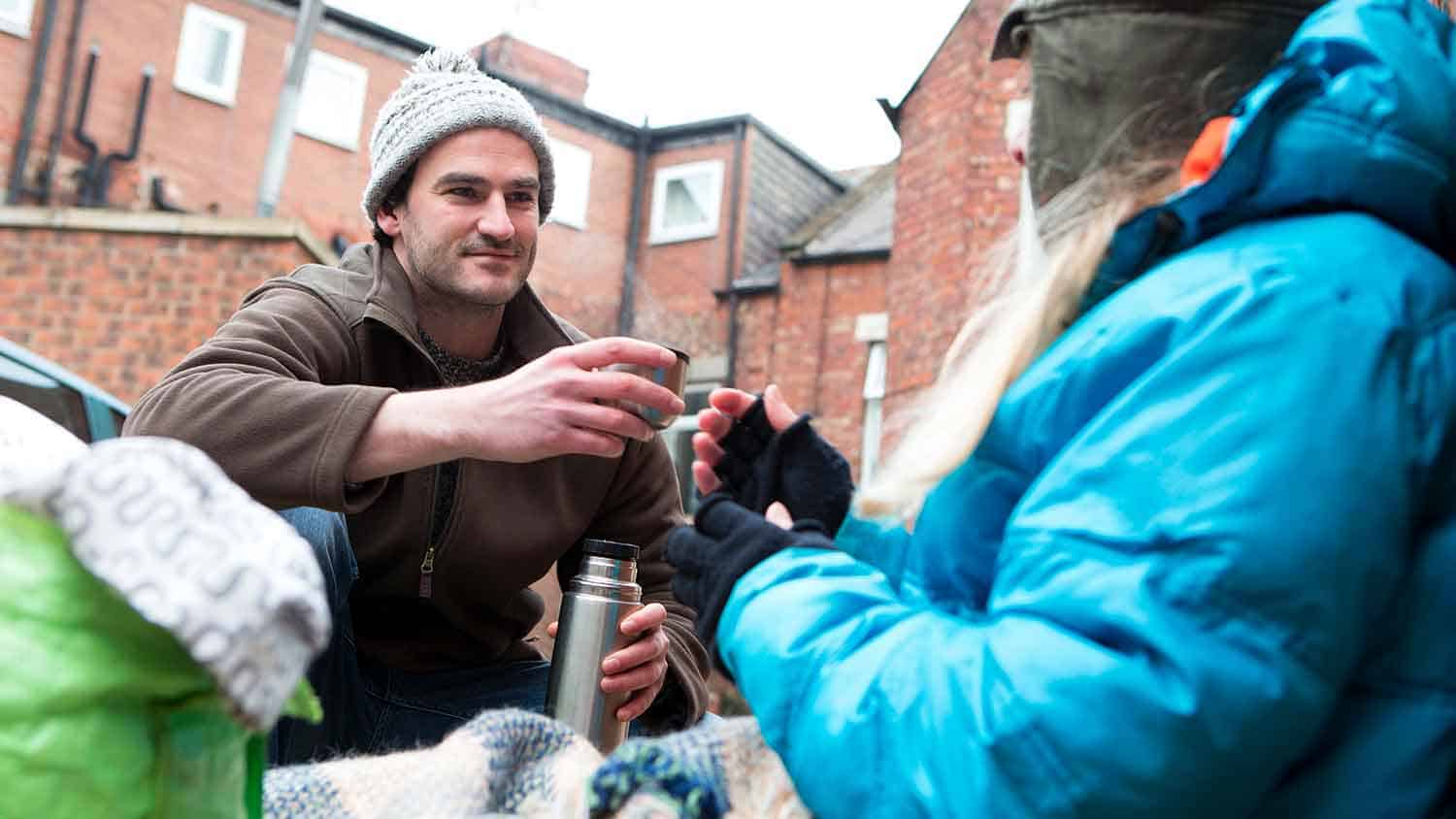 A volunteer sharing a cup of tea with a homeless person