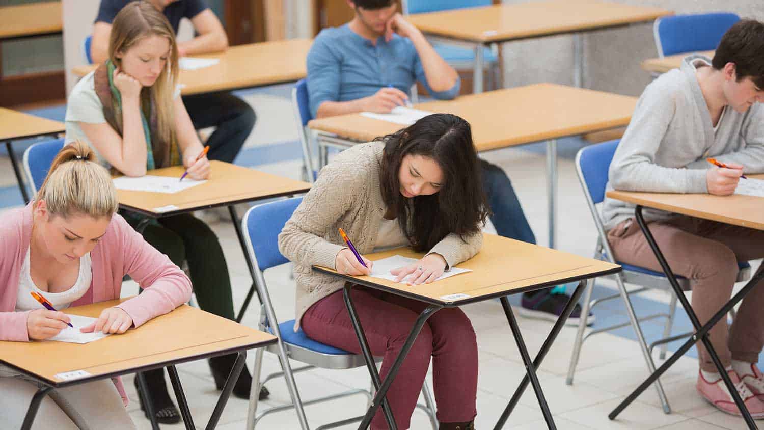 Pupils taking an exam writing on tables