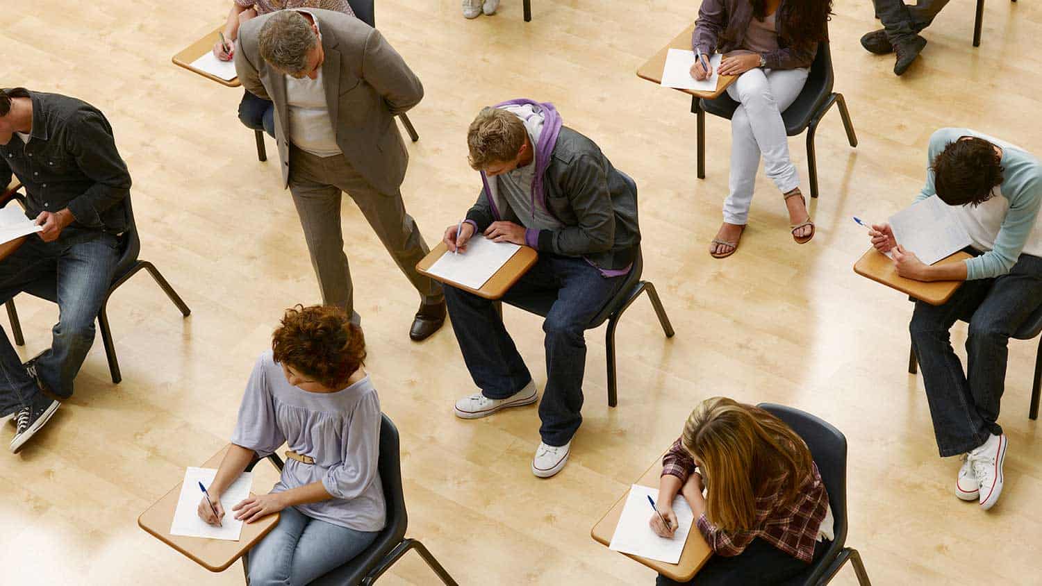 Students taking an exam sitting on isolated chairs