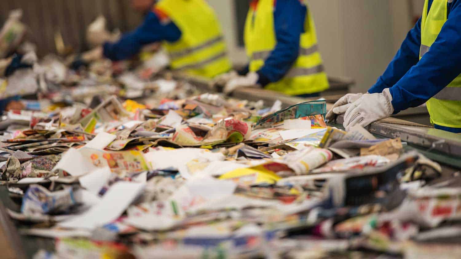 Workers sorting through a conveyor line of recyling