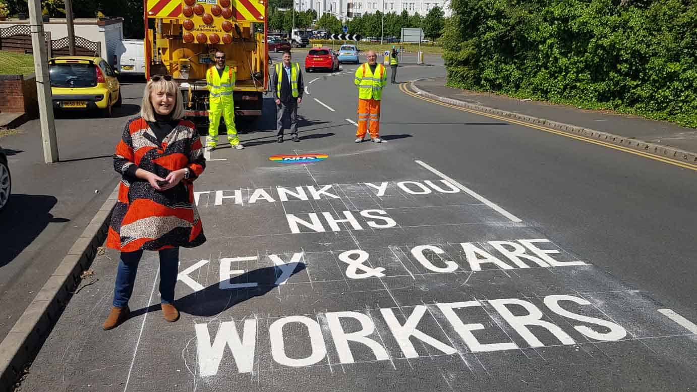 Highways team next to a 'thank you key workers' sign on the road written in chalk