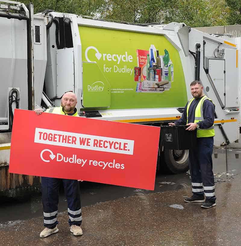 Recyling pick up truck with two workers holding a 'together we recycle' sign