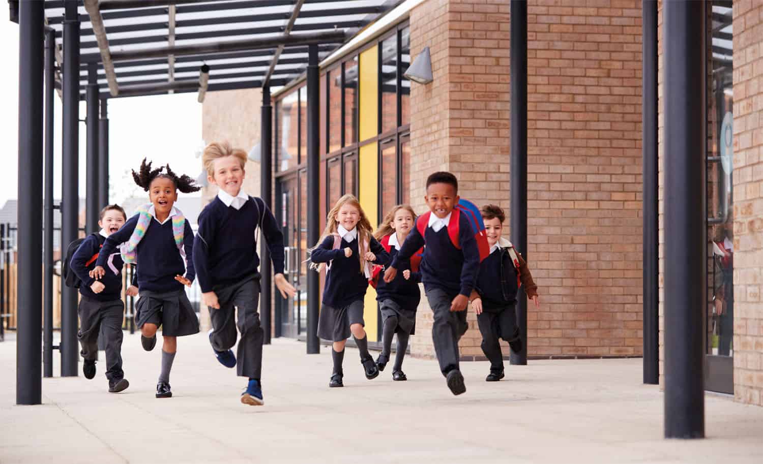 A group of school children running excitedly out of the building