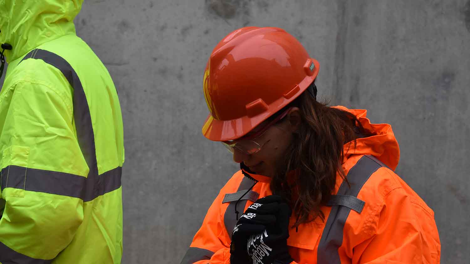 A construction worker with a red hard hat and orange hi-vis