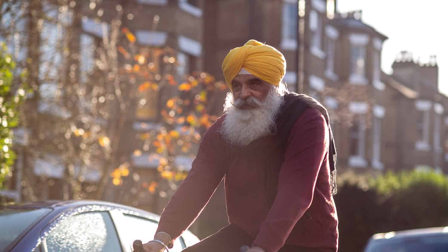 Sikh man wearing a yellow turban riding a bicycle