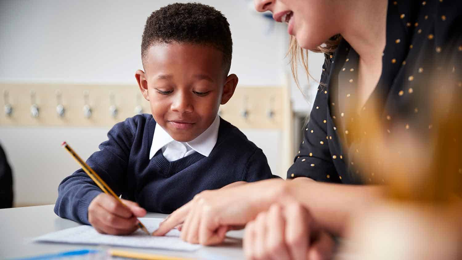 Young student working with a teacher.