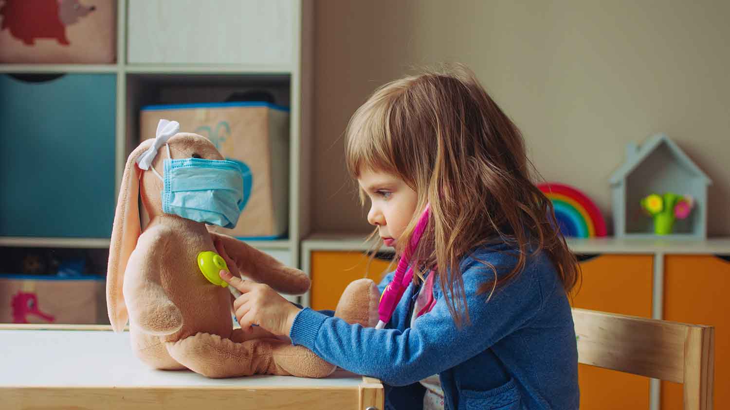 Young toddler with a toy stethascope and using it on a stuffed toy