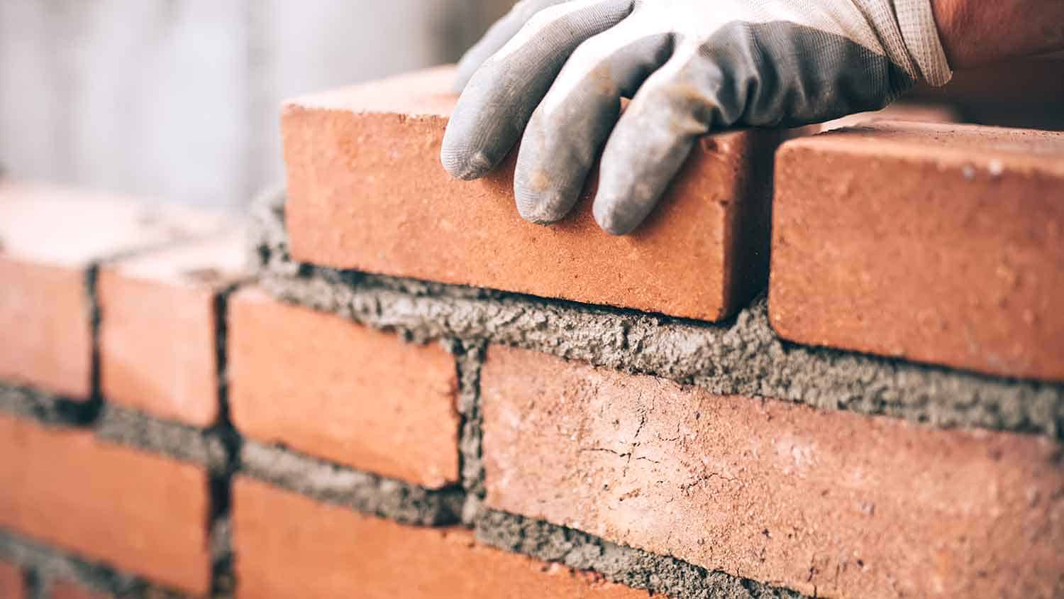 Bricklayer cementing down bricks