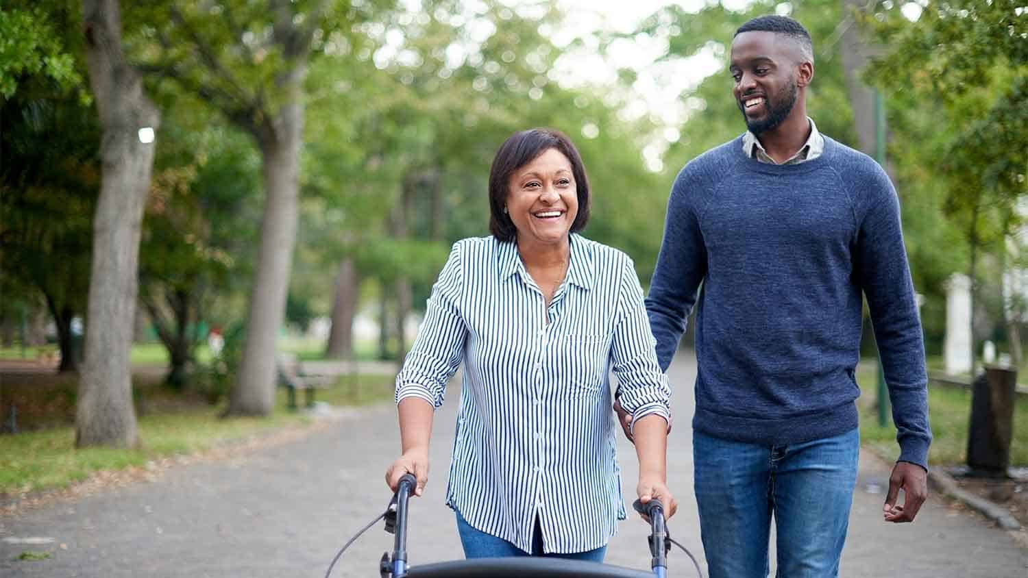 Man walking next to a woman using a walking aide