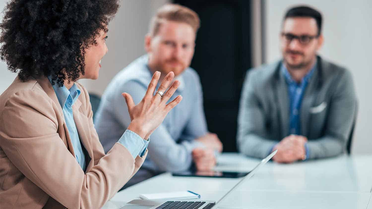 Three office workers talking at a table