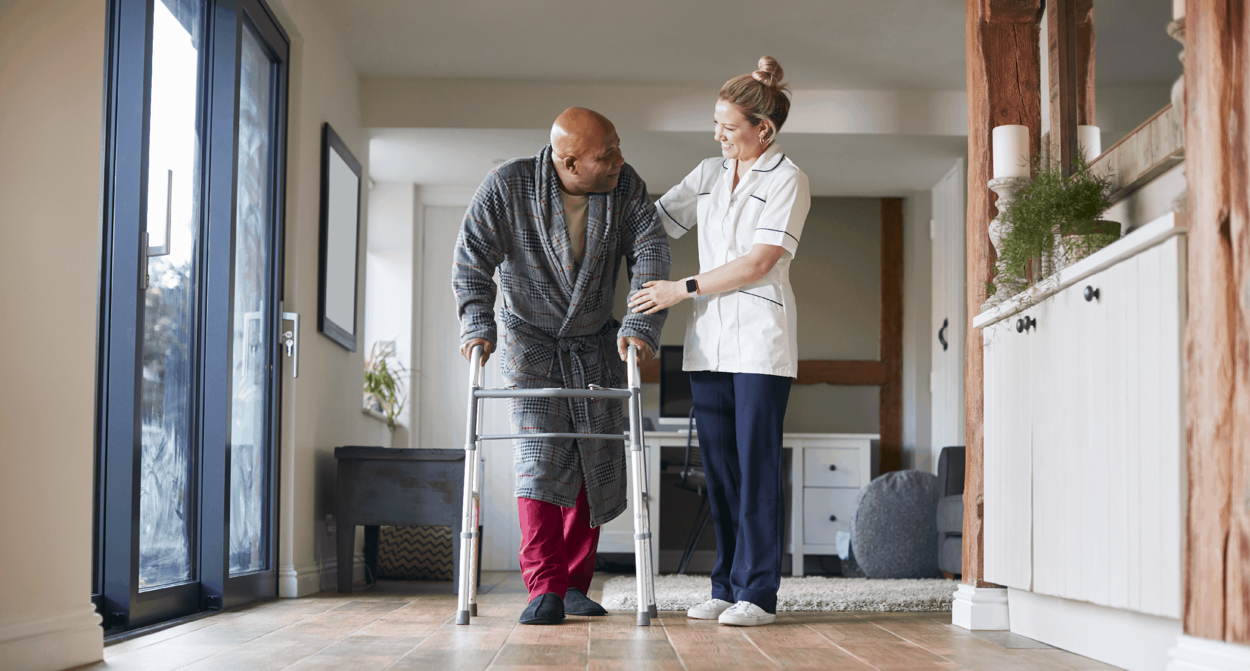 A patient being helped along the corridor by a carer