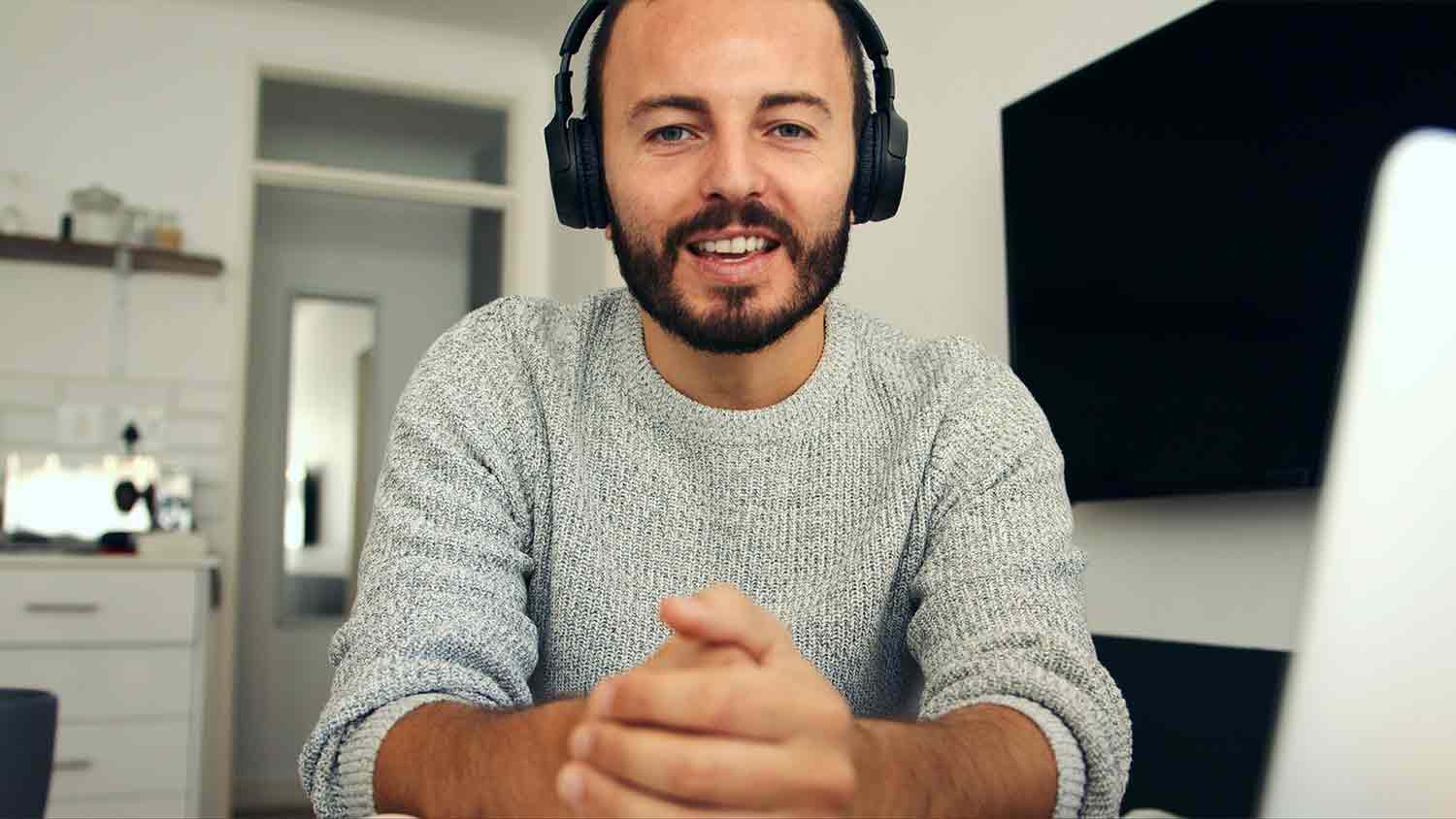 A bearded man looking at the camera whilst wearing headphones