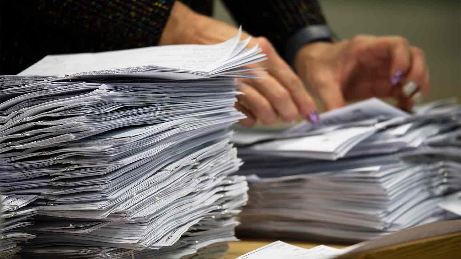 A woman flicking through a pile of papers