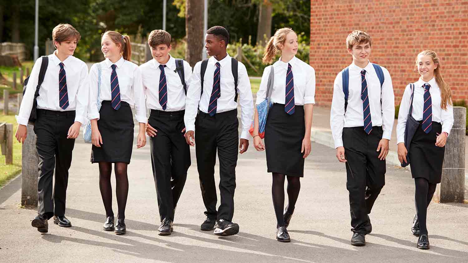 Seven school children in uniform, no blazers, confidently walking down a path