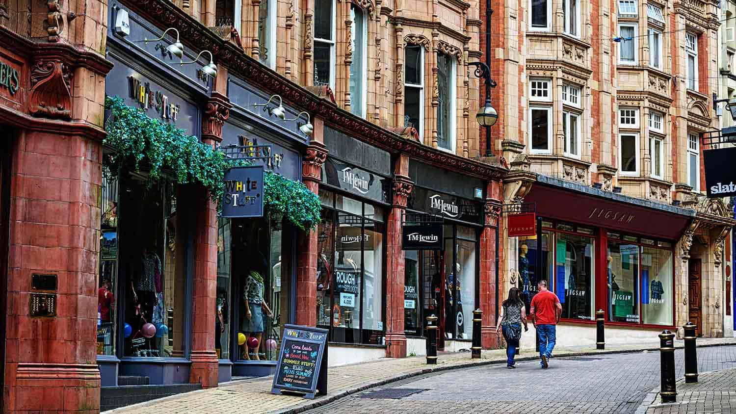 High street of an older cobbled city. The shops are modern.