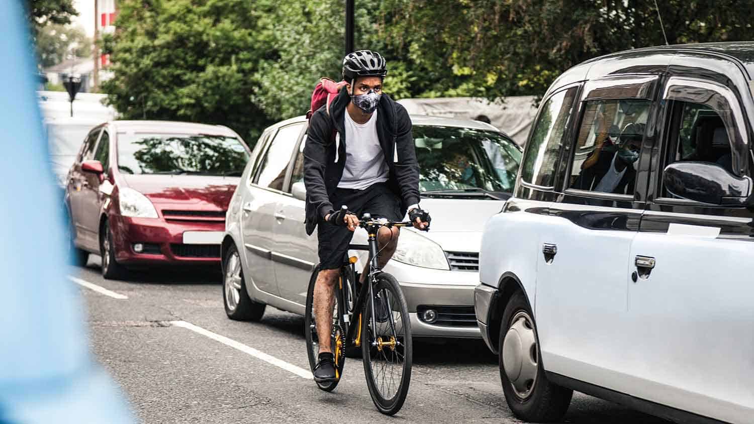 Cyclist with a face mask riding through traffic