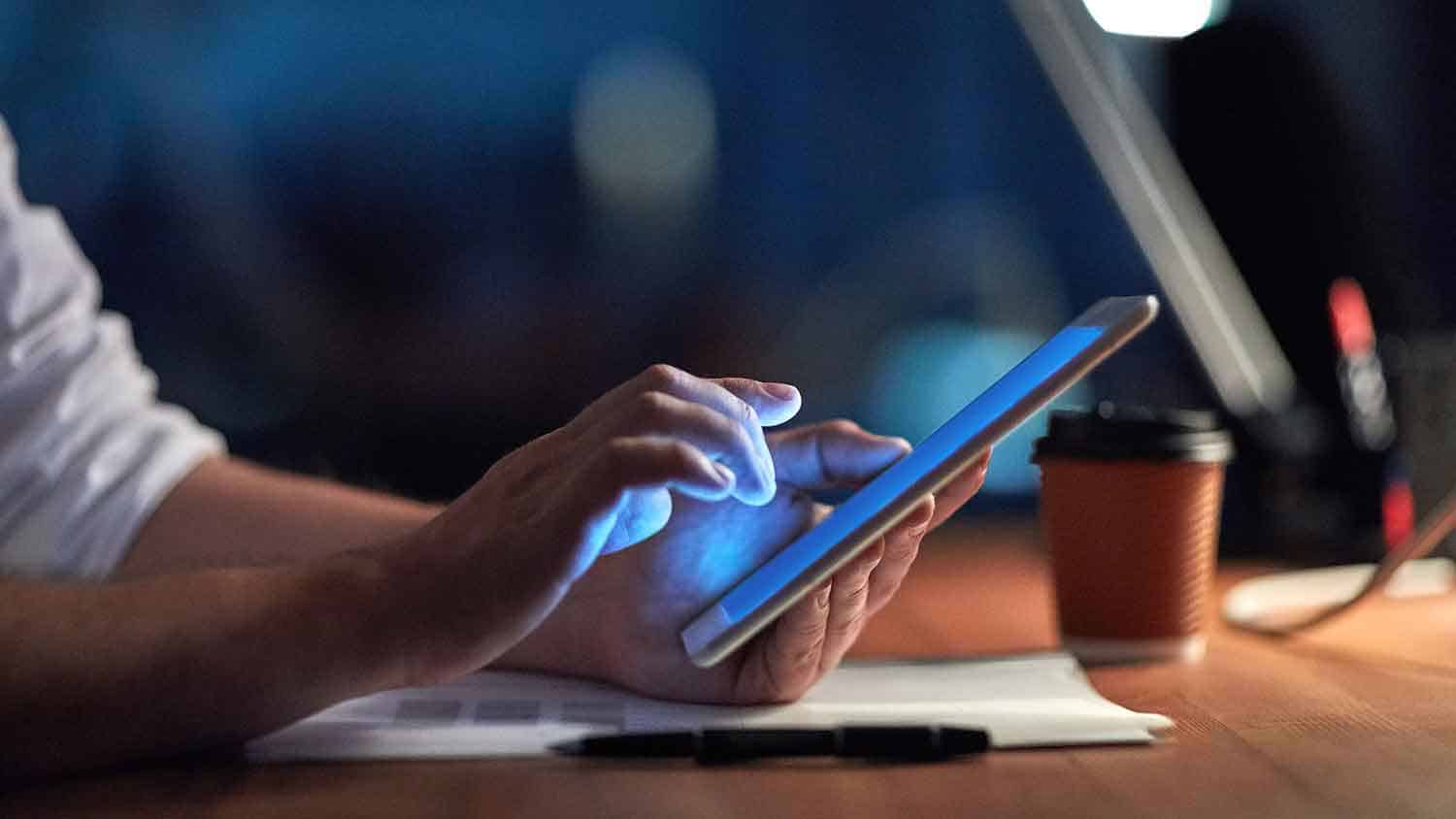 someone working on an ipad in the dark. The screen is glowing.