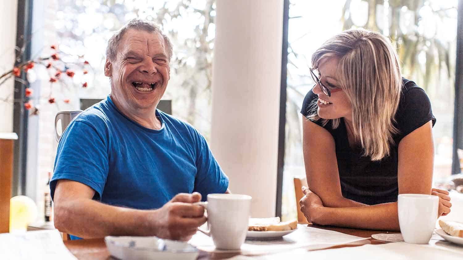 A man with down syndrome enjoying coffee with someone