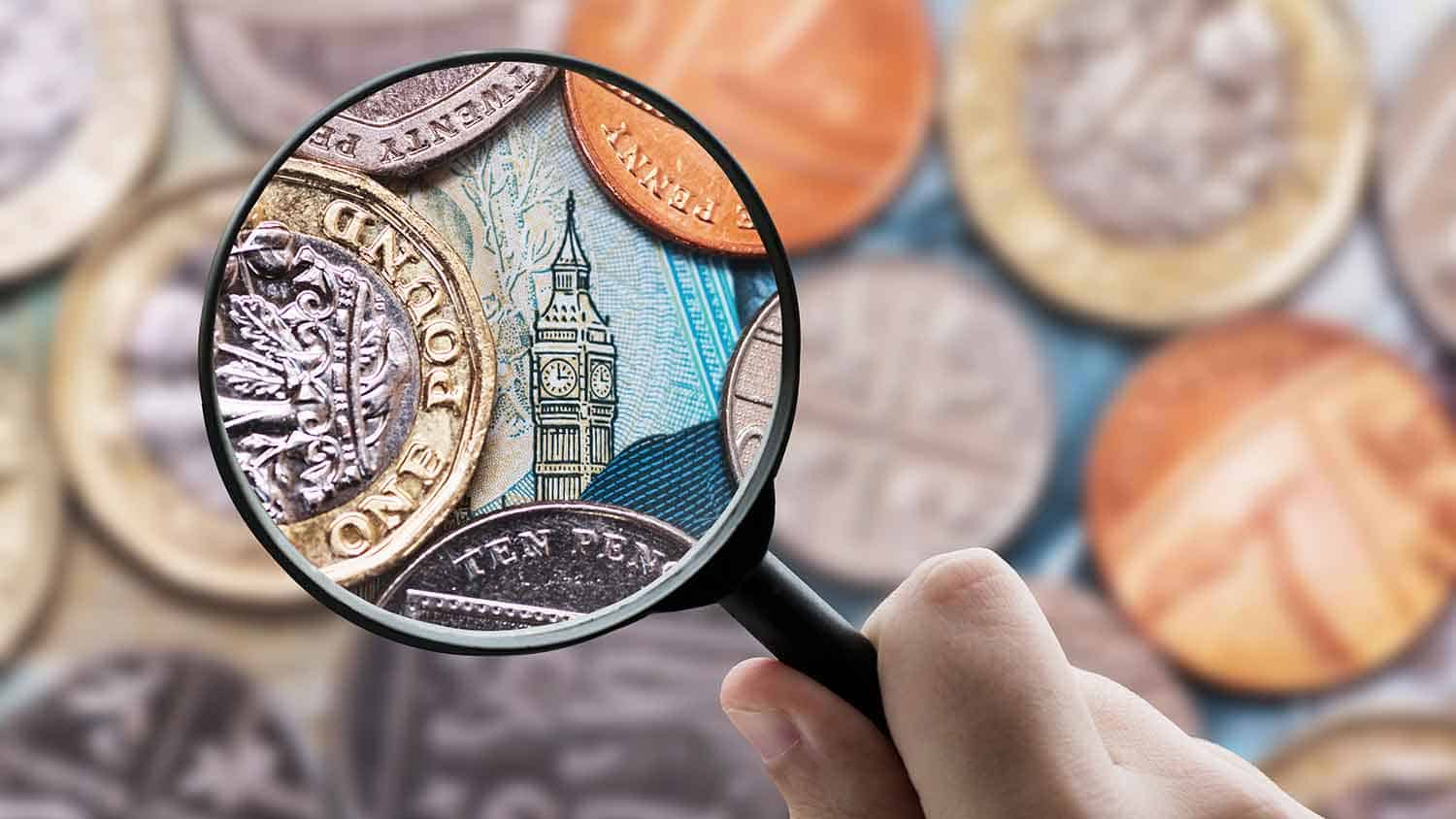 Magnifying glass looking closely at a five pound note