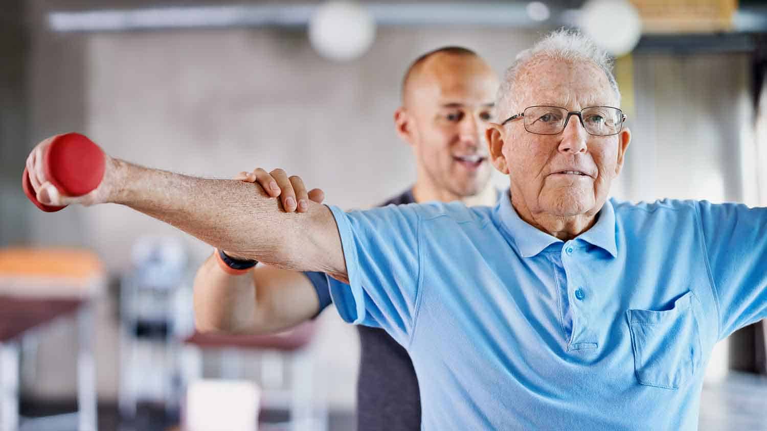 a rehab trainer helping an older man with shoulder mobility exercises