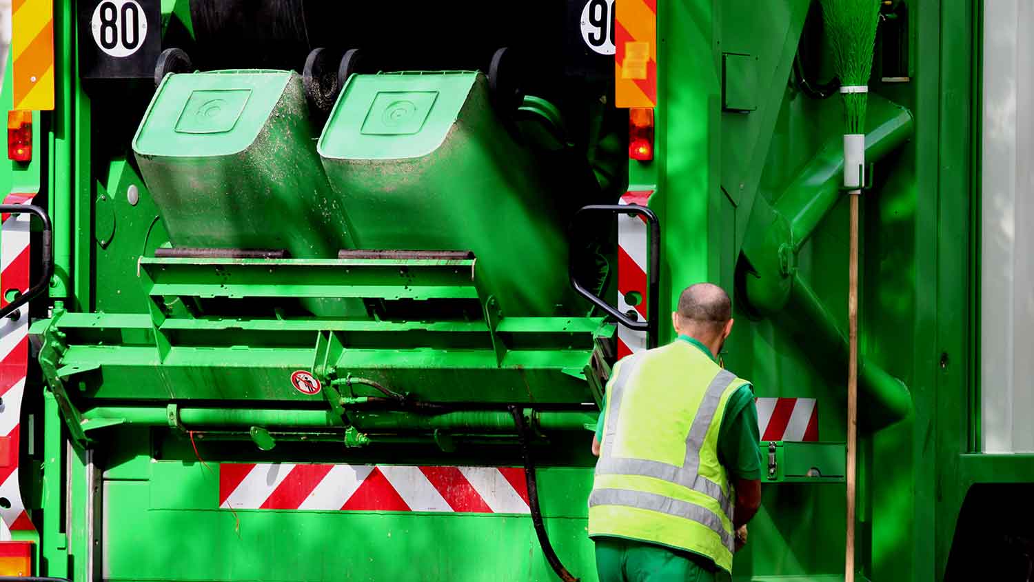 a green bin lorry tipping two bins into the truck