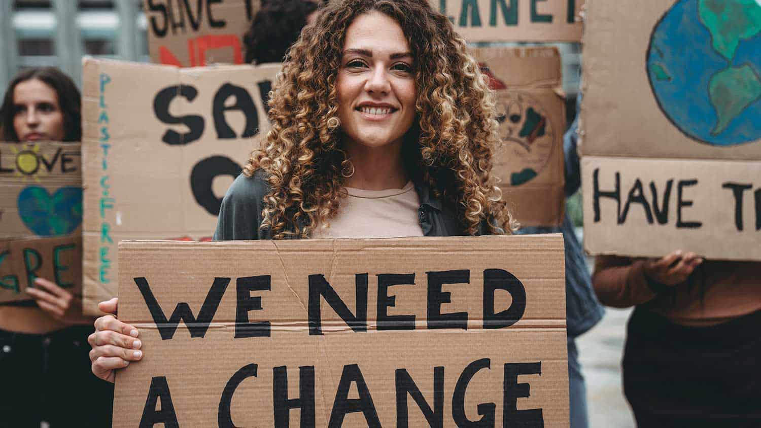 Climate campaigner with a 'we need change' sign