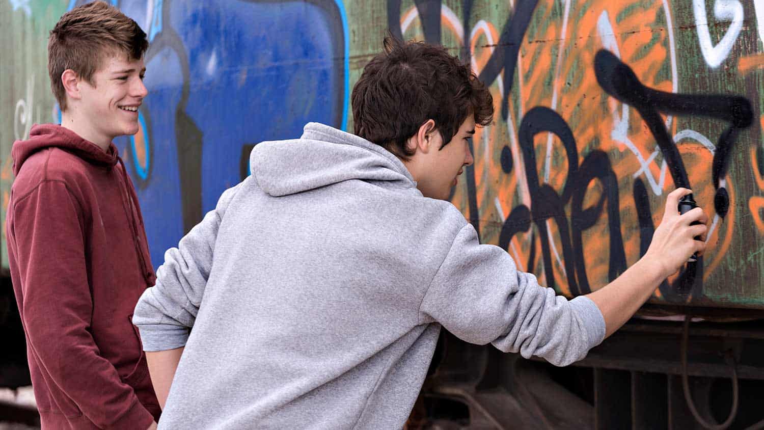 Two teenage boys practicing graffiti