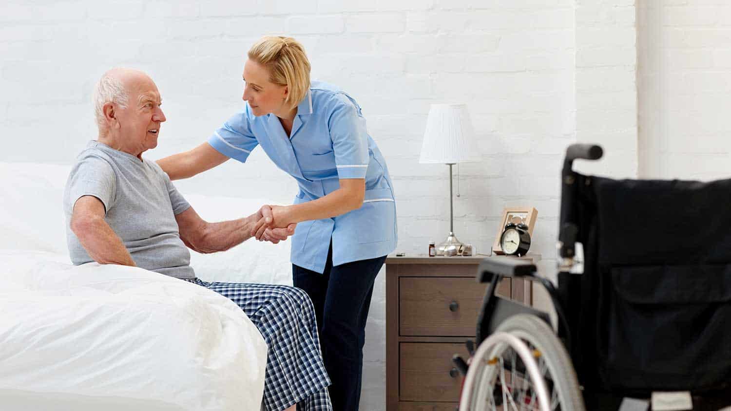 Nurse helping an older man from bed