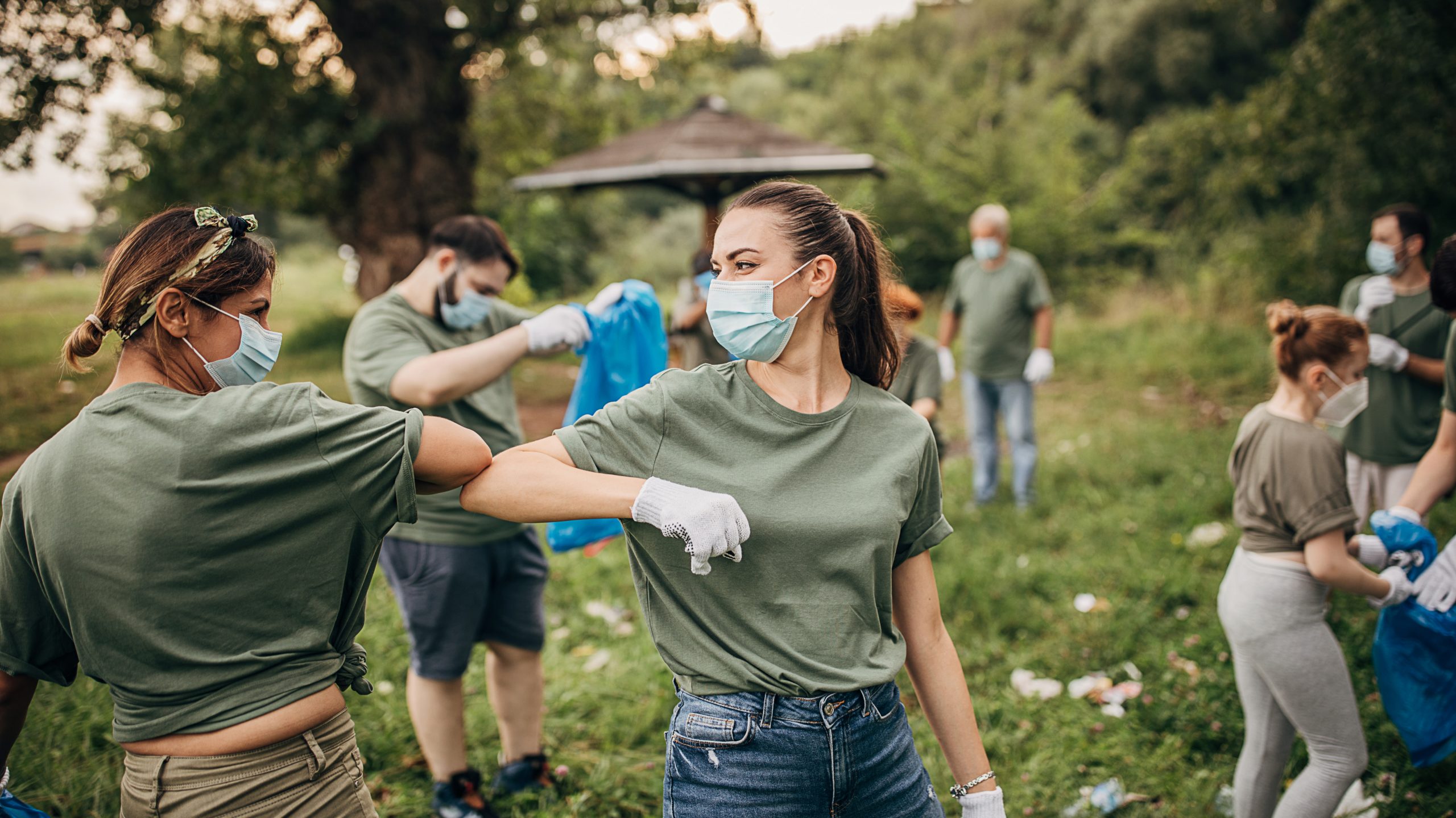 Group of volunteers with face masks cleaning a park together