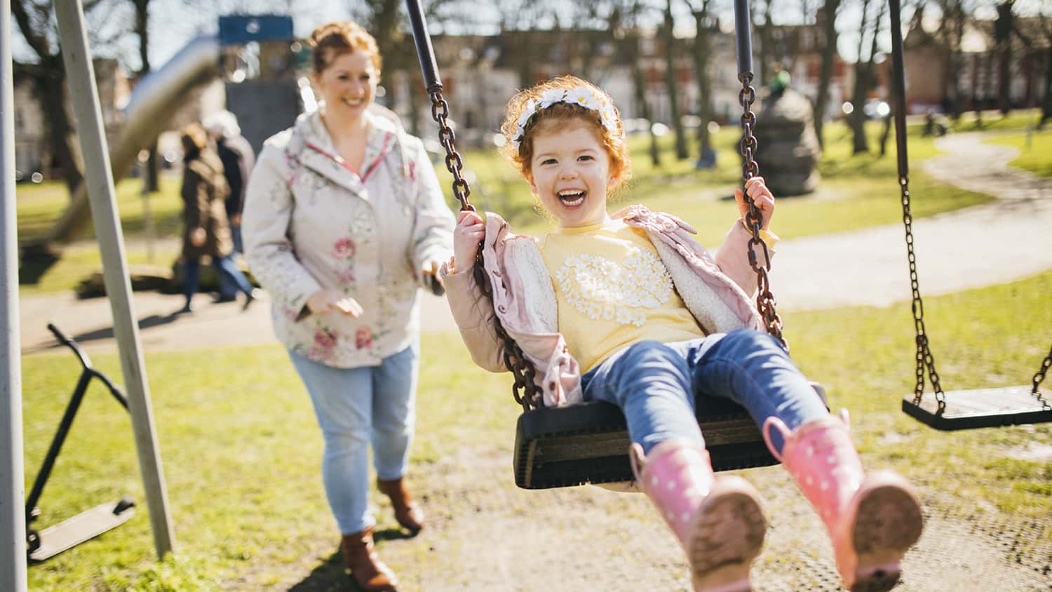 Little girl being pushed on a swing by her mother