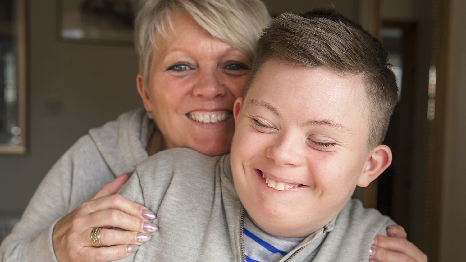 Young boy with down syndrome being hugged by guardian