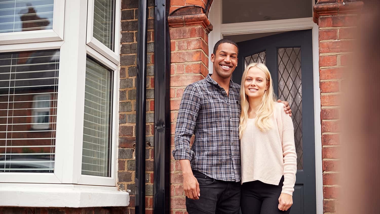 Young couple standing together outside door of home