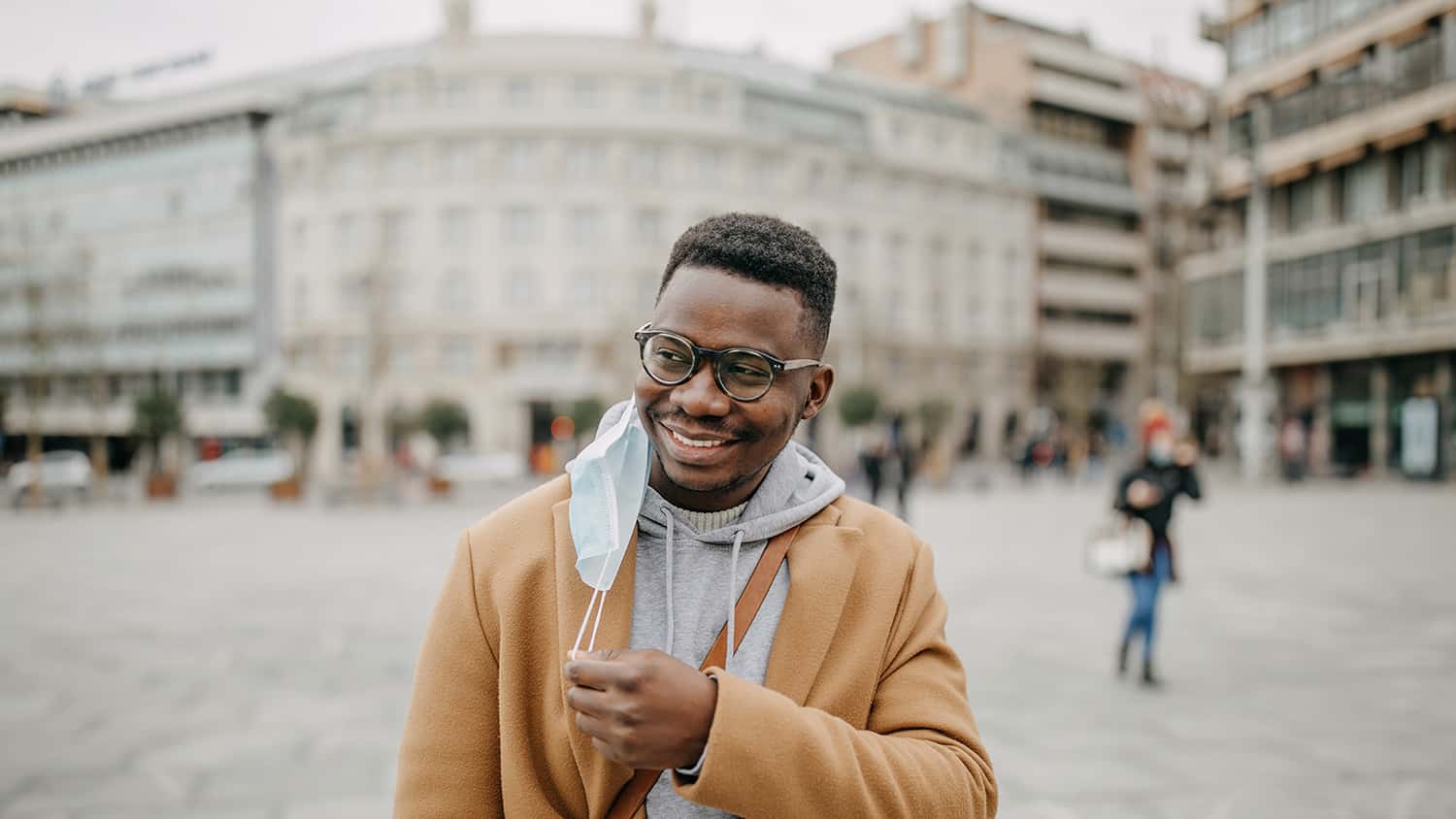 Smiling man standing outside in a town centre.