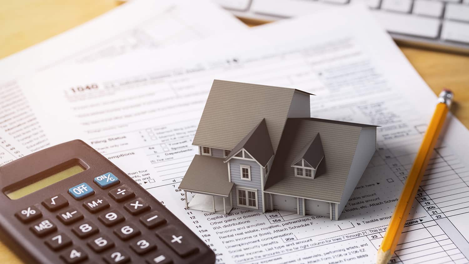 A tiny model of a house and a calculator on paperwork.