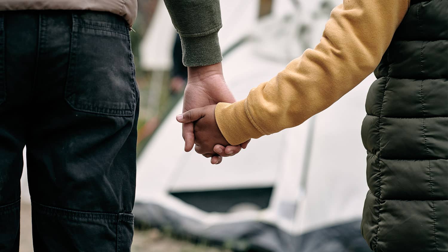 A child and their father holding hands