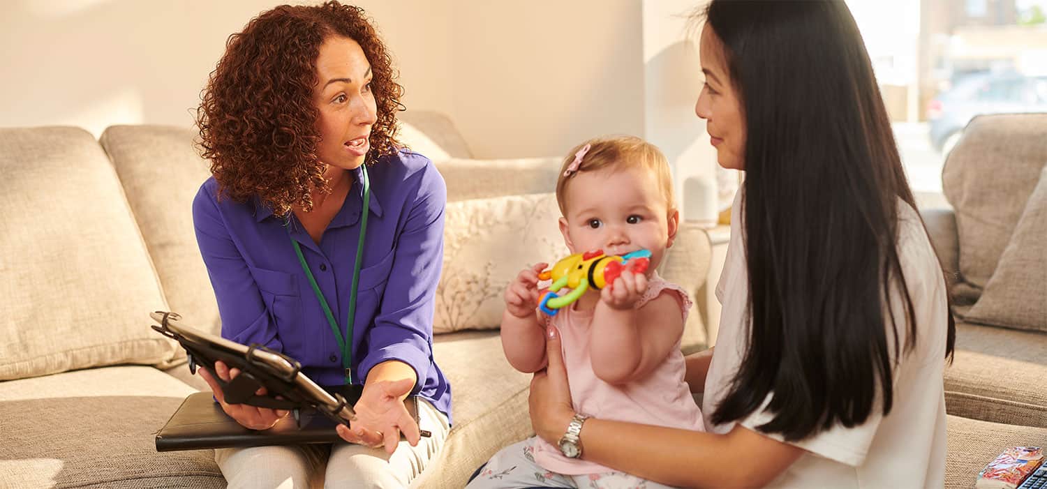 A mother and her baby getting help from a health professional