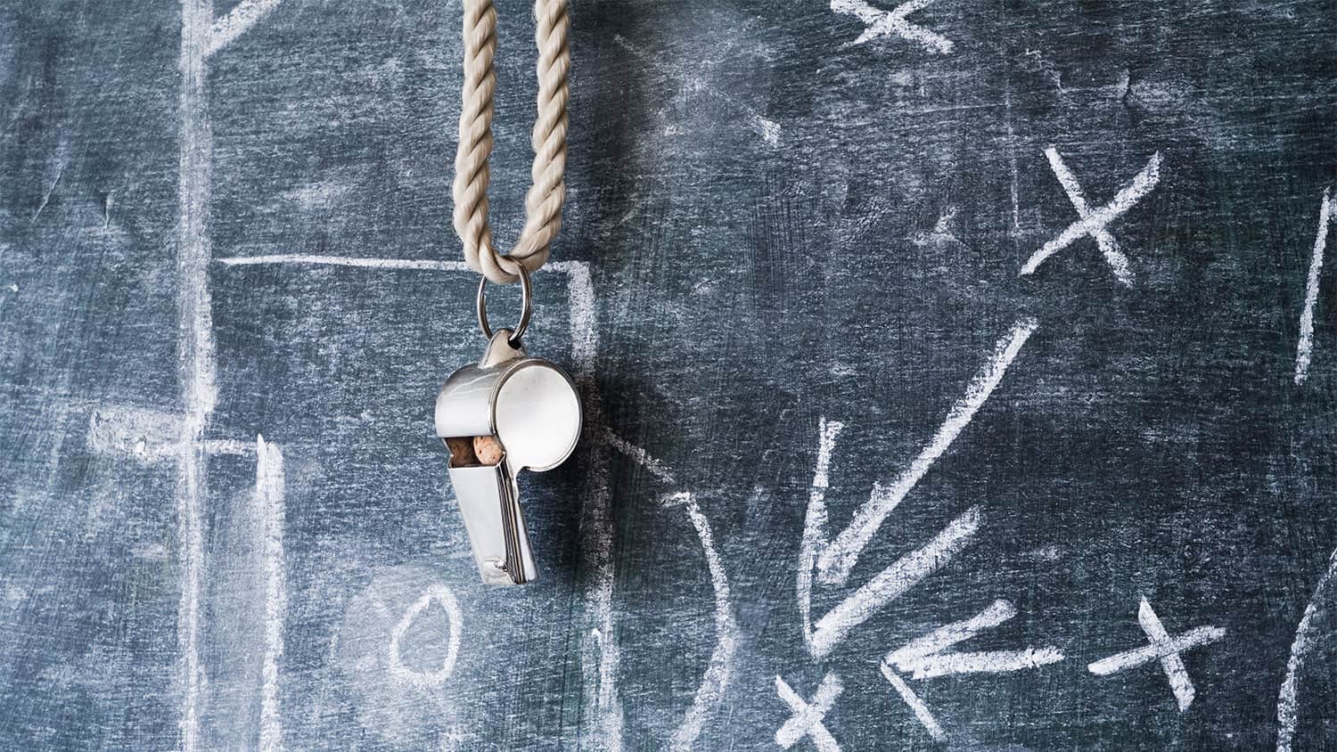 A teacher's whistle hanging on a blackboard
