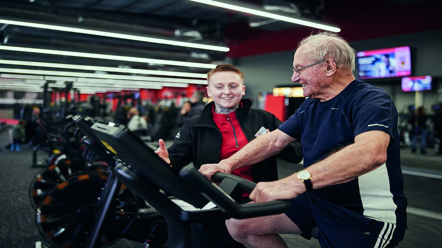 Older man on an exercise bike at White Oak Leisure Centre with a personal trainer