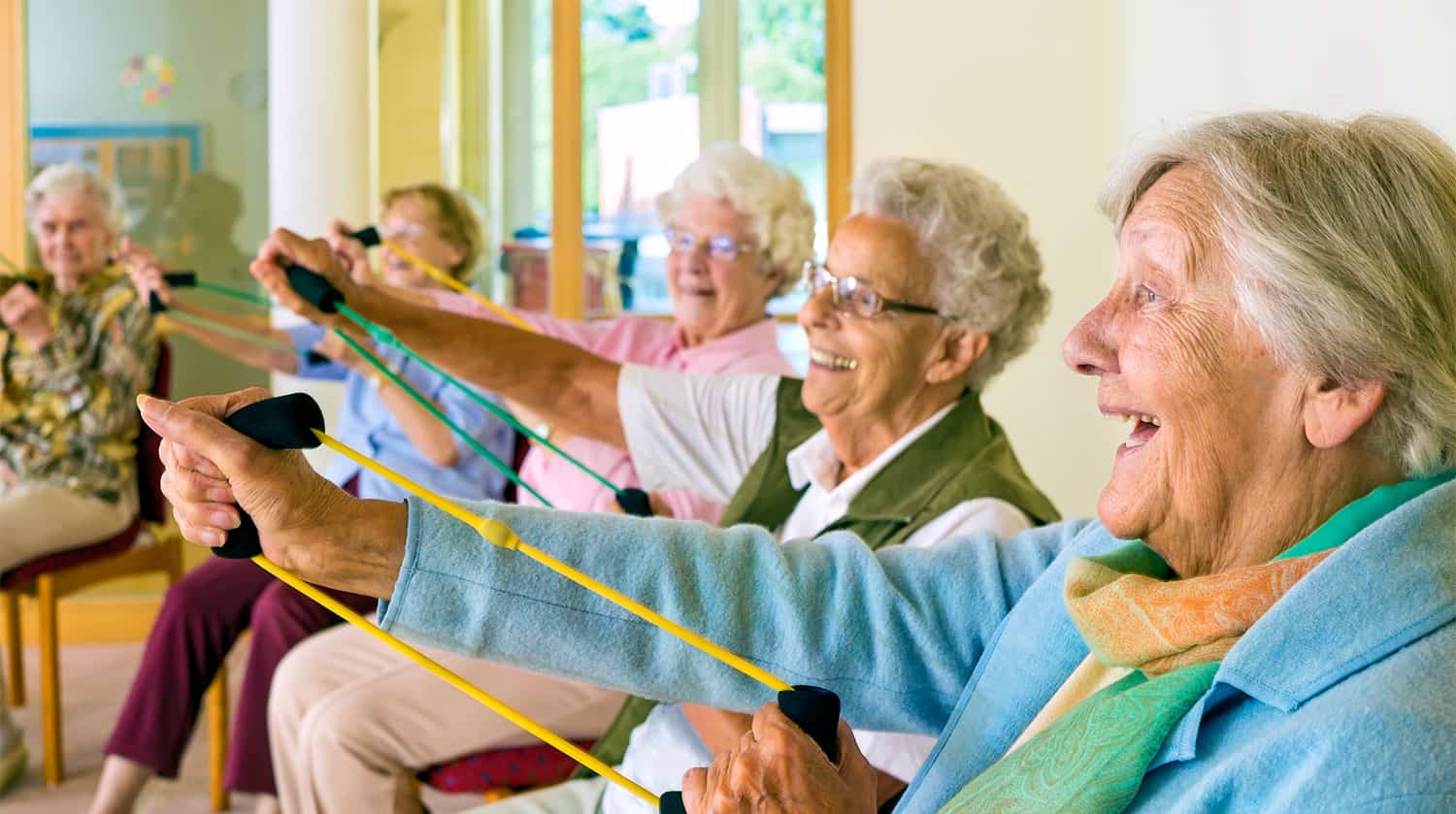 Elderly ladies sat down doing some arm exercises