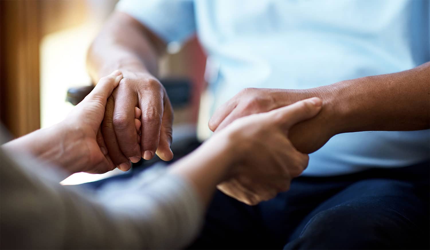 A carer holding hands with their patient