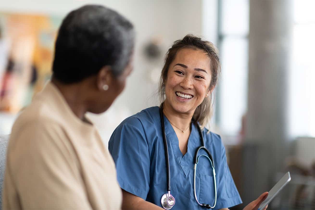 Young doctor speaking to an older lady and smiling