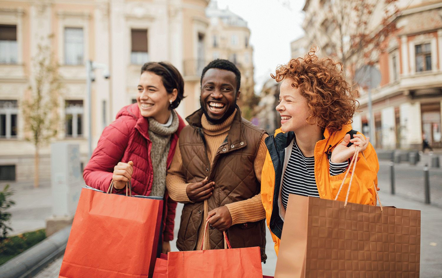 Three people with shopping bags smiling