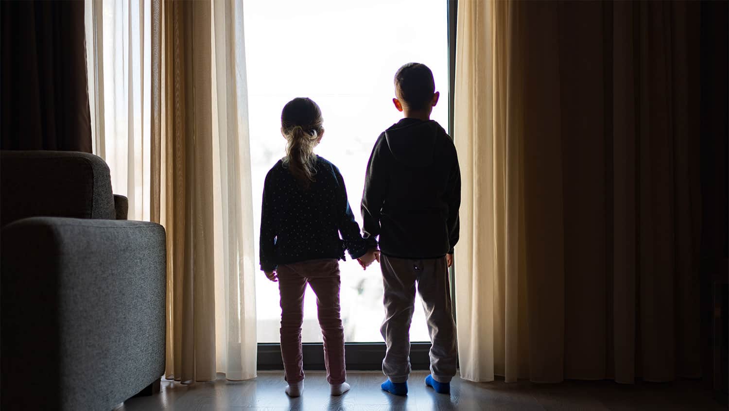 A young boy and girl stood by a window